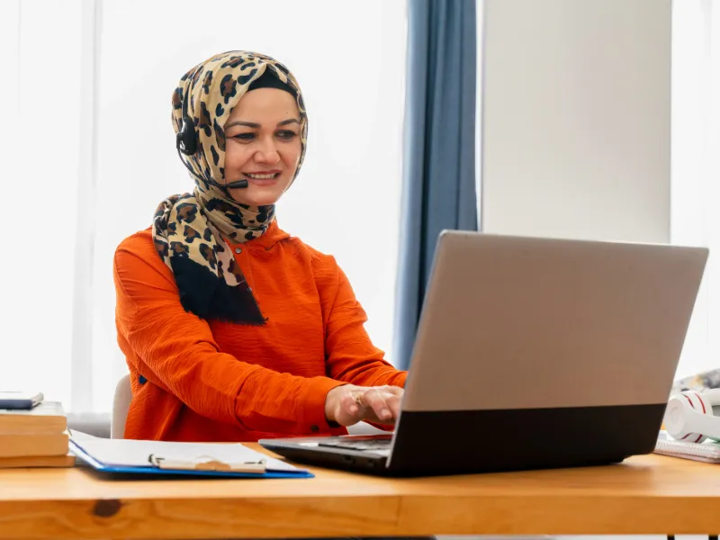 Woman wear headset looks at laptop talk by videocall
